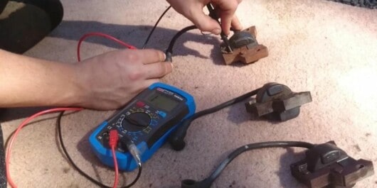 person testing chainsaw coil resistance using a multimeter