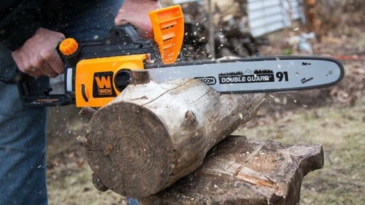 man cutting logs using chainsaw